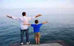 Father and young boy with arms stretched upwards